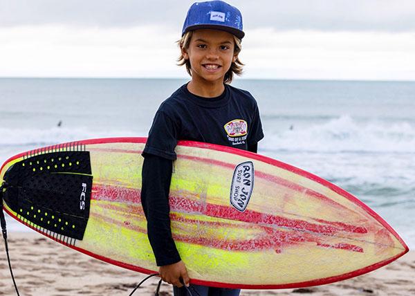 Photo of Sebastian Peters holding a surfboard at the beach